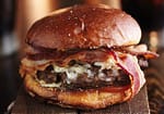 A burger with bacon, maple syrup, and fried egg.