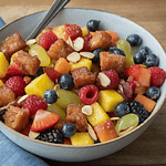 Cider donut croutons on top of a fruit salad.