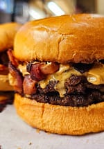 A big juicy burger with peanut butter and bacon on it.
