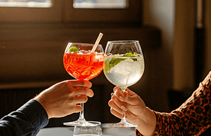 Two people clanking wine glasses together.