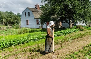 A lady wearing 1830's clothing sweeping her sidewalk in the village