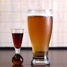 A glass of dark whiskey and a large glass of beer.