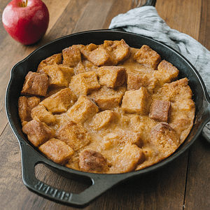 A cast iron pan with cider donut bread pudding in it.